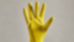 Hand holding up 5 fingers wearing yellow latex gloves.