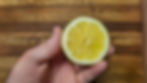 A hand holding a lemon cut in half.